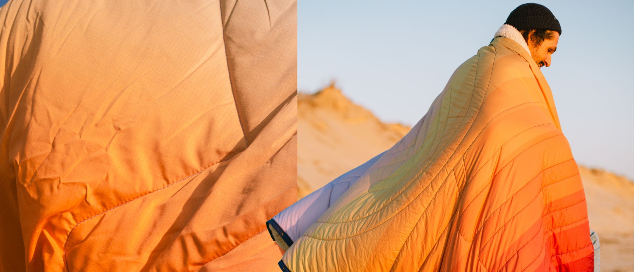 A quilted puffer blanket with a soft white sherpa collar, shown in a close-up detail view on the left and worn by a person in a desert setting on the right. The blanket features a vibrant gradient pattern transitioning from orange and yellow to light blue and purple. CloudTouch® Blanket
